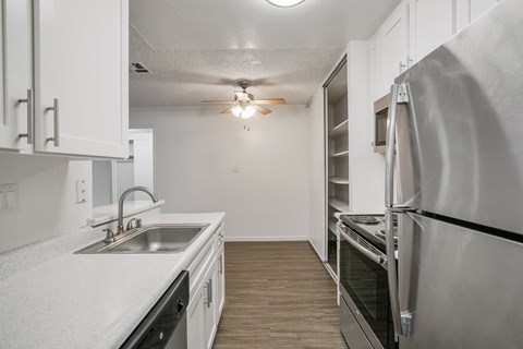 A kitchen with white cabinets and a stainless steel refrigerator.