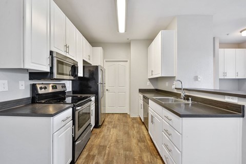 A kitchen with white cabinets and black countertops.