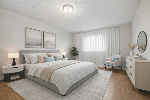A well-lit bedroom with a large bed, a chair, and a side table.