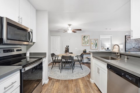 A modern kitchen with a dining table and chairs in the middle.
