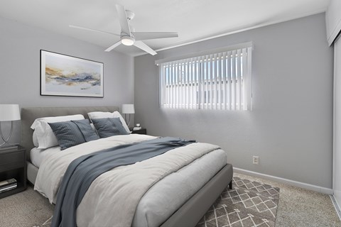 A bedroom with a large bed and a ceiling fan.