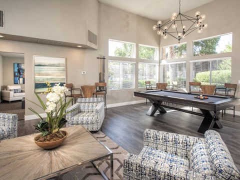A living room with a pool table and a large window.