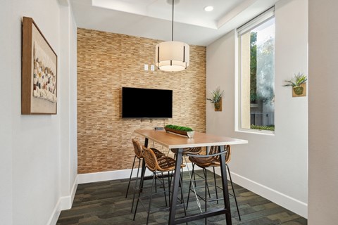 A dining room with a brick wall and a flat screen TV.