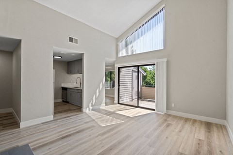 an open living room and kitchen with a sliding glass door to a patio