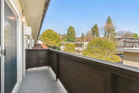 A balcony with a view of trees and houses.