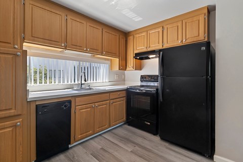 A kitchen with wooden cabinets and a black refrigerator.