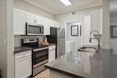 A kitchen with white cabinets and a stainless steel counter.