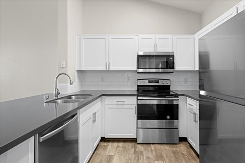 A modern kitchen with white cabinets and stainless steel appliances.