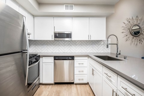 A modern kitchen with white cabinets and stainless steel appliances.