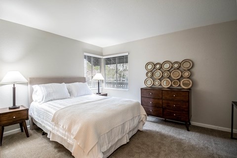 A bedroom with a bed, nightstand, and a dresser with plates on it.