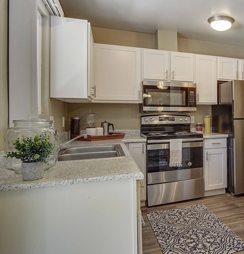 A kitchen with white cabinets and a stainless steel refrigerator.