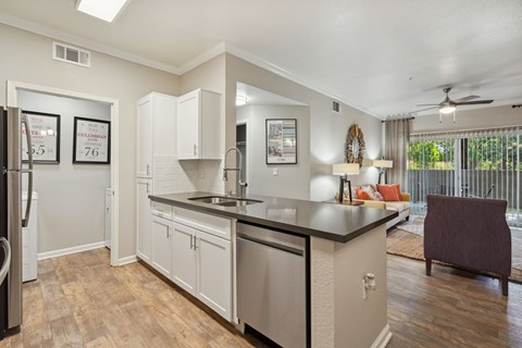 A kitchen with white cabinets and a black countertop.