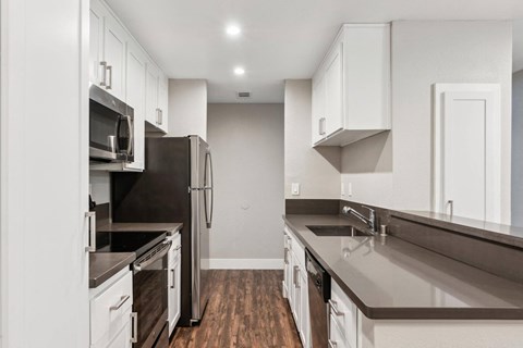 A kitchen with white cabinets and dark countertops.