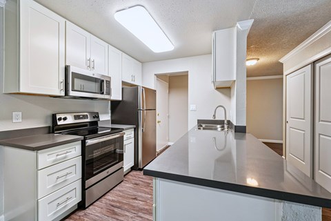 A kitchen with a black countertop and white cabinets.