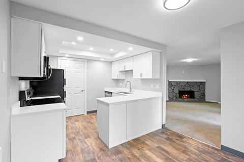 A modern kitchen with white cabinets and a black stove top oven.