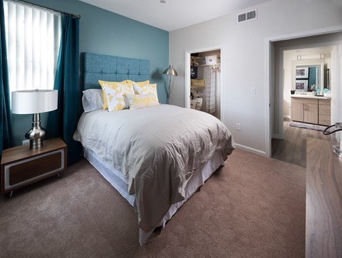 A bedroom with a large bed and a lamp on a side table.