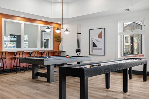 A pool table in a room with a chair, a mirror, and a framed picture on the wall.