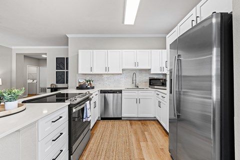 A modern kitchen with white cabinets and stainless steel appliances.
