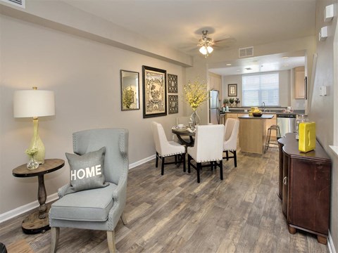 A living room with a grey chair and a table with a lamp on it.