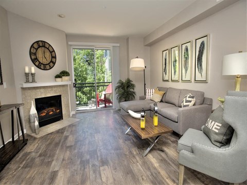 A living room with a grey couch and a fireplace.