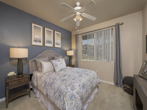 A bedroom with a bed, nightstands, and a ceiling fan.