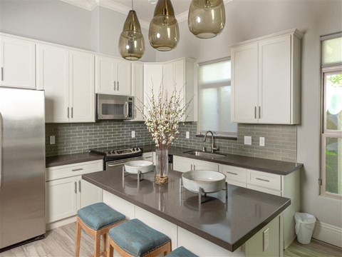 A kitchen with white cabinets and a black countertop.