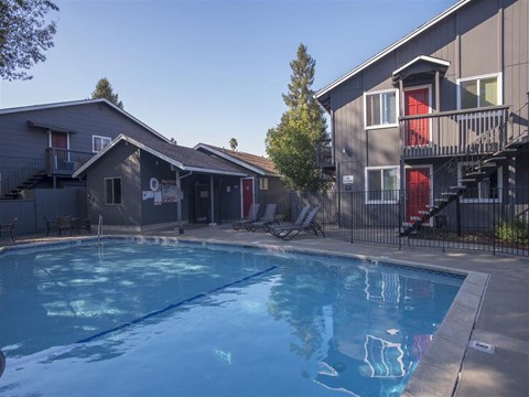 A swimming pool in a backyard with a house in the background.