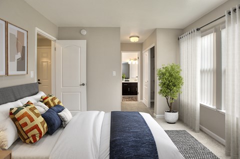 A bedroom with a large bed and a potted plant.