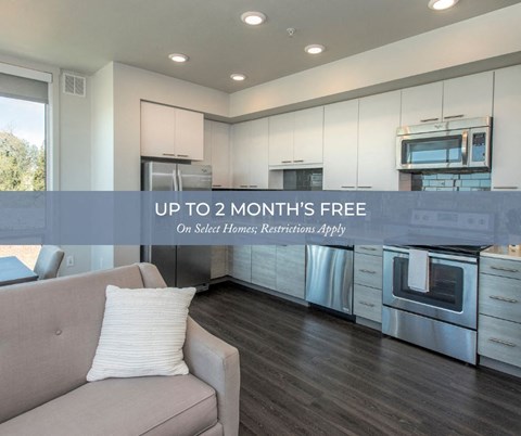 A modern kitchen with a couch and a pillow, offering up to 2 months free on select homes.