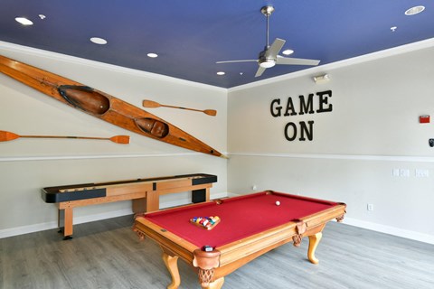 A pool table with a red cloth and a wooden frame is in the center of the room.