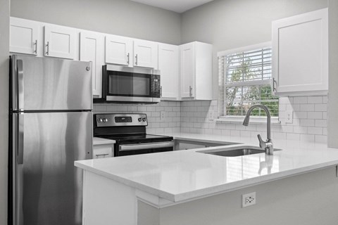 A kitchen with white cabinets and appliances.