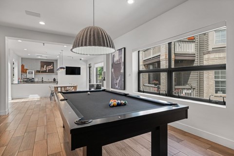 A pool table is in the middle of a room with a light hanging from the ceiling.