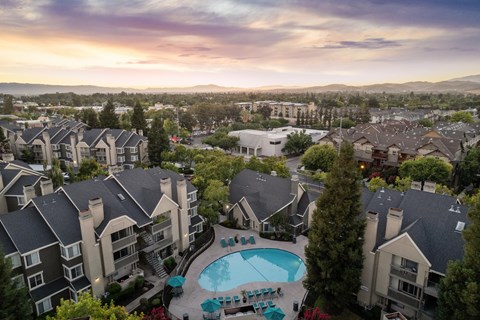 A large apartment complex with a swimming pool in the foreground.