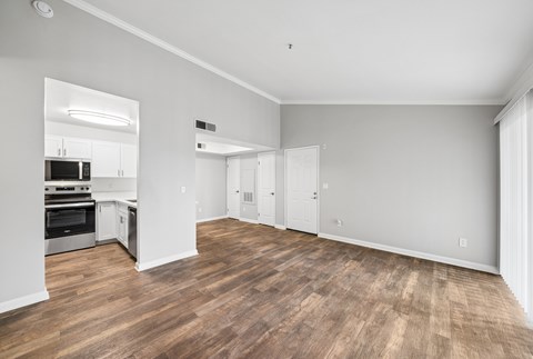 A spacious room with wooden flooring and white walls.