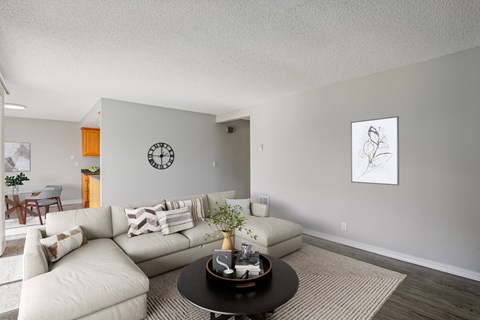 A living room with a white couch and a clock on the wall.