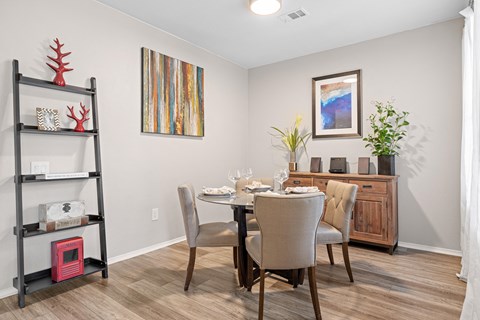 A dining room with a table set for two and a painting on the wall.