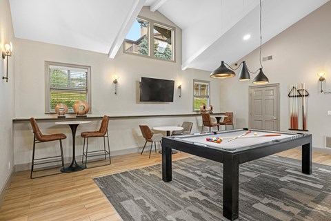 A room with a pool table and a tv.