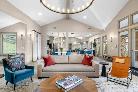 A living room with a blue chair, a beige couch, and a coffee table with a book on it.