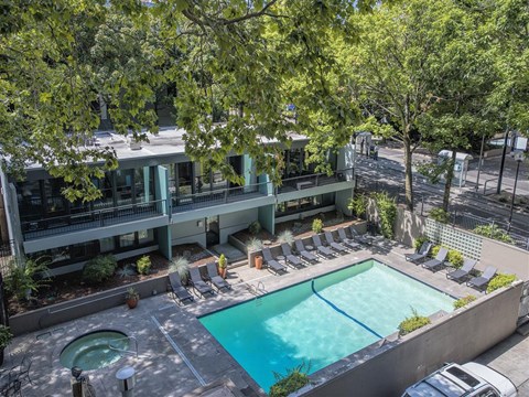 A swimming pool surrounded by lounge chairs and trees.
