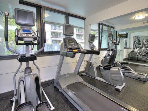 A gym with treadmills, exercise bikes, and a television.