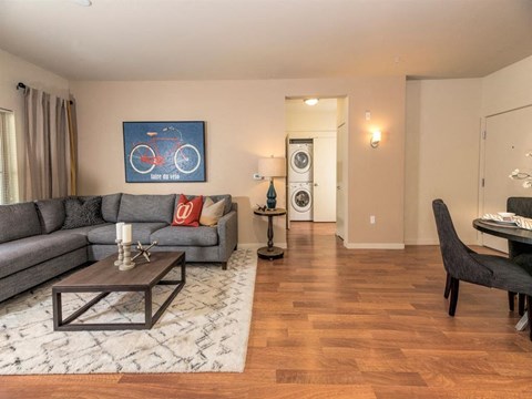 A living room with a grey couch, a coffee table, and a painting of a red bicycle on the wall.
