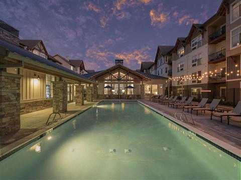 A large indoor swimming pool with lounge chairs and a building in the background.