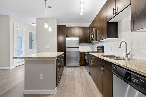 A modern kitchen with dark wood cabinets and stainless steel appliances.