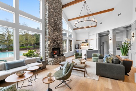 A living room with a stone fireplace and a large window.