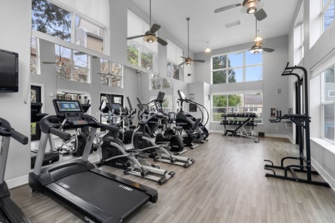 A spacious gym with a variety of equipment and a flat screen TV mounted on the wall.