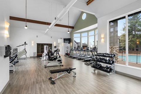 A gym with a variety of equipment including treadmills, weights, and exercise machines.