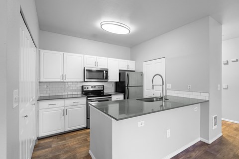 A kitchen with white cabinets and a black countertop.