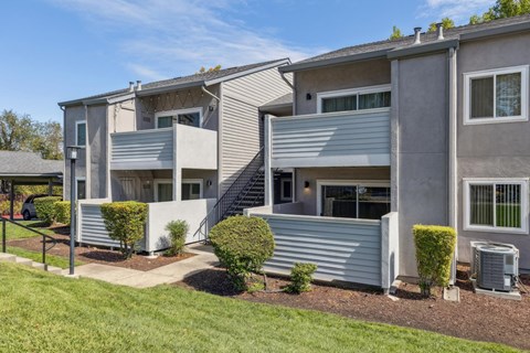 A modern two-story apartment building with a well-maintained lawn and landscaping.