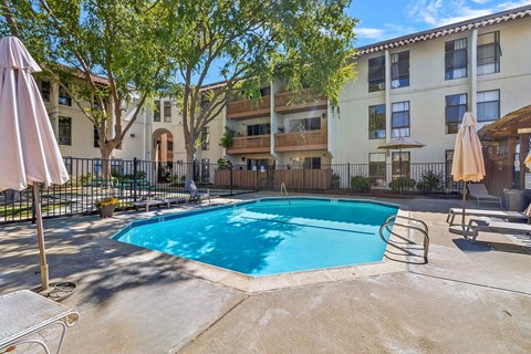 A pool surrounded by a fence and trees.