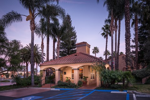 A house with a red tile roof is surrounded by palm trees.